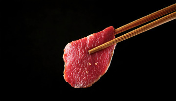 新鲜的牛肉片，色泽鲜红，纹理清晰，被一双筷子轻轻夹起1