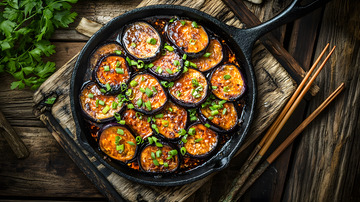 陶铁板上的香煎茄子与葱花点缀的经典风味