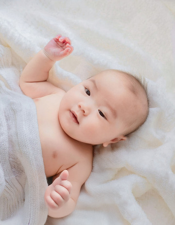 婴儿躺在柔软的白色毛毯上