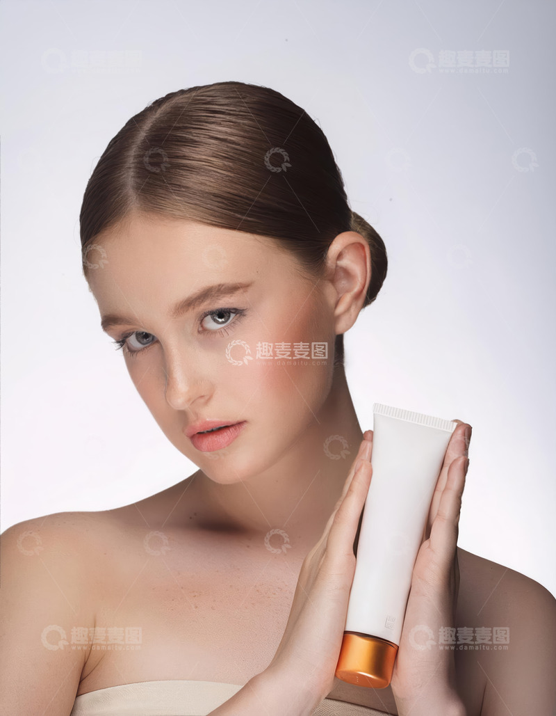 高清大图下载【趣麦麦图】一位女性，她的头发梳成一个发髻，面容姣好，皮肤白皙，眼神明亮且富有神采。她双手捧着一个米色的护肤品软管，背景为浅色，整体画面给人一种清新、优雅且时尚的感觉1