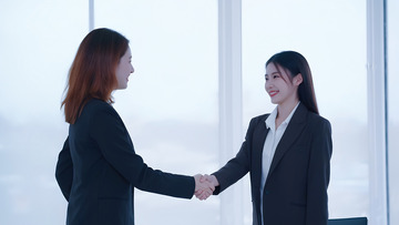 两位女性在一个明亮的室内环境中握手的场景