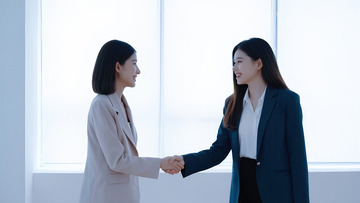 两位女性在一个明亮的室内环境中握手的场景1