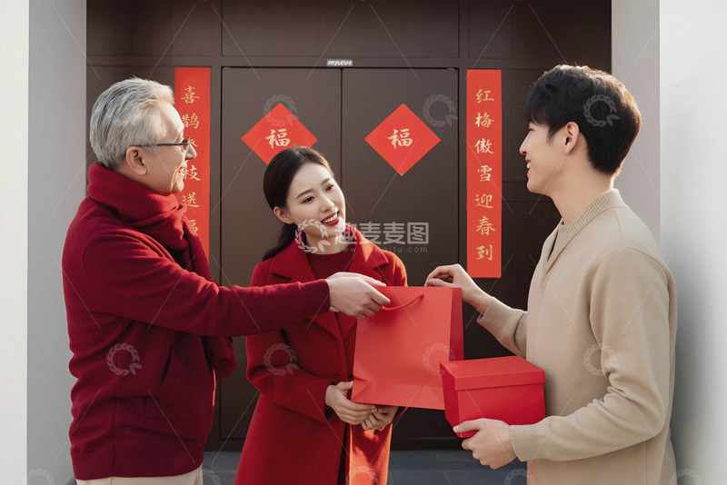高清大图下载【趣麦麦图】一位穿着红色衣服的老人正将一个红色购物袋递给一位同样穿着红色衣服的女子女子身旁是一位穿着米色衣服的男子手中拿着红色礼盒