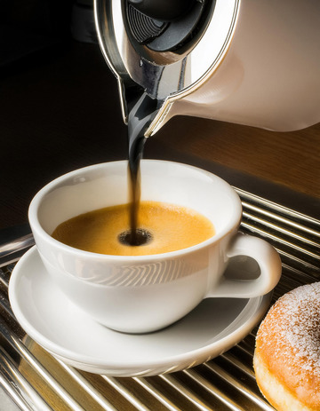 一杯正在被倒入咖啡的白色咖啡杯