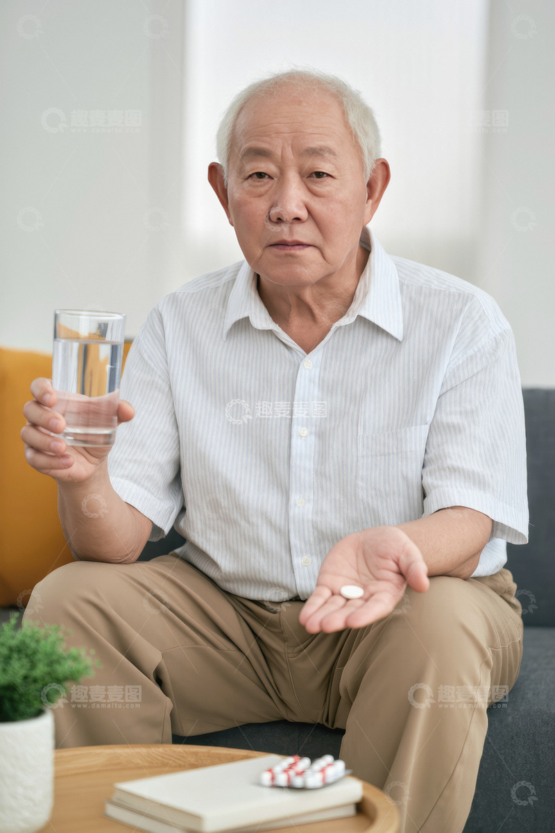 高清大图下载【趣麦麦图】一位头发花白的老爷爷他穿着浅色的衬衫坐在室内的椅子上手里拿着药片和水杯似乎正准备服药1