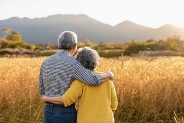 一对老年夫妻在金黄的麦田中相拥的温馨场景