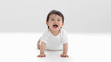 一个穿着白色衣服的婴儿，双手和双膝撑在白色的平面上，咧着嘴开心地笑着，展现出活泼可爱的模样1