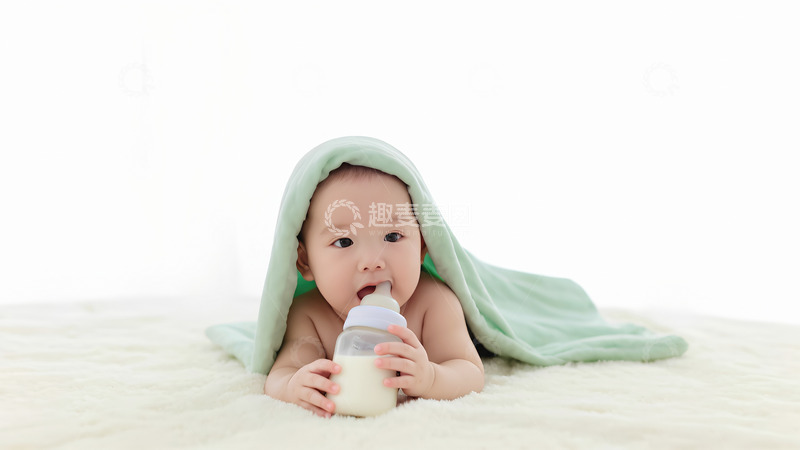 高清大图下载【趣麦麦图】一个裹着浅绿色毯子的婴儿双手捧着奶瓶
