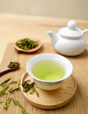 白色的茶壶，茶杯和茶托，杯中盛有泡开的绿茶，茶叶在茶汤中舒展开来，色泽嫩绿1