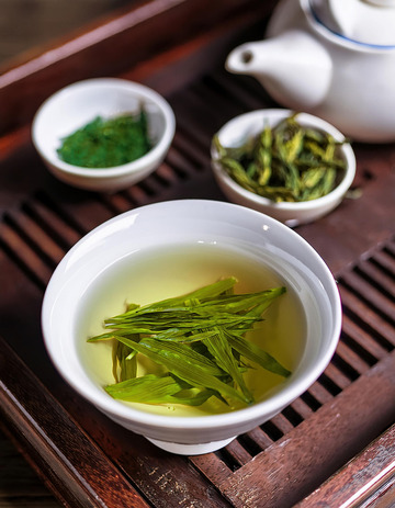 深色茶盘上摆放着白色的茶壶
