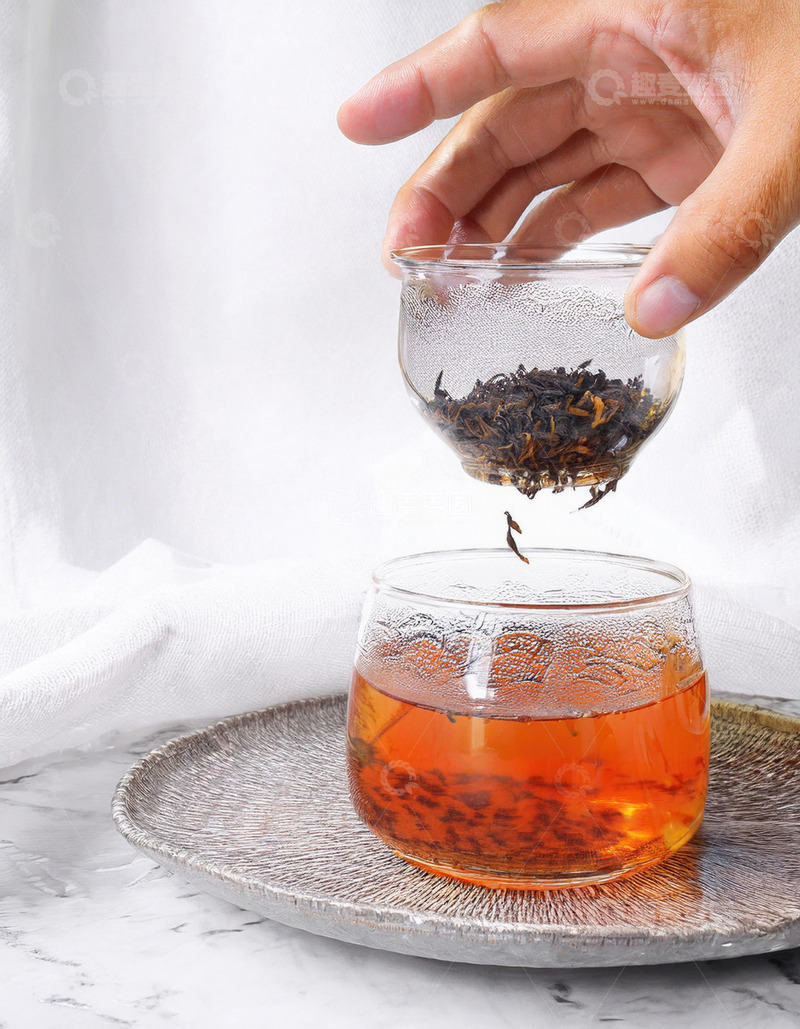 高清大图下载【趣麦麦图】一只手正拿着一个透明小茶杯，将其中的红茶茶叶倒入下方装有茶汤的透明大玻璃杯中1
