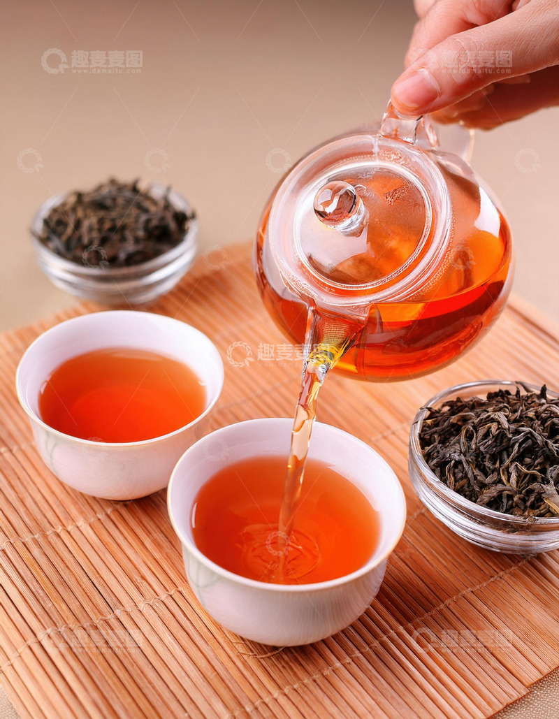 高清大图下载【趣麦麦图】一只手正握着透明的玻璃茶壶，往白色的茶杯中倾倒橙红色的红茶茶汤