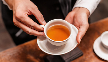 双手端起装有红茶的白色茶杯及茶托的场景2