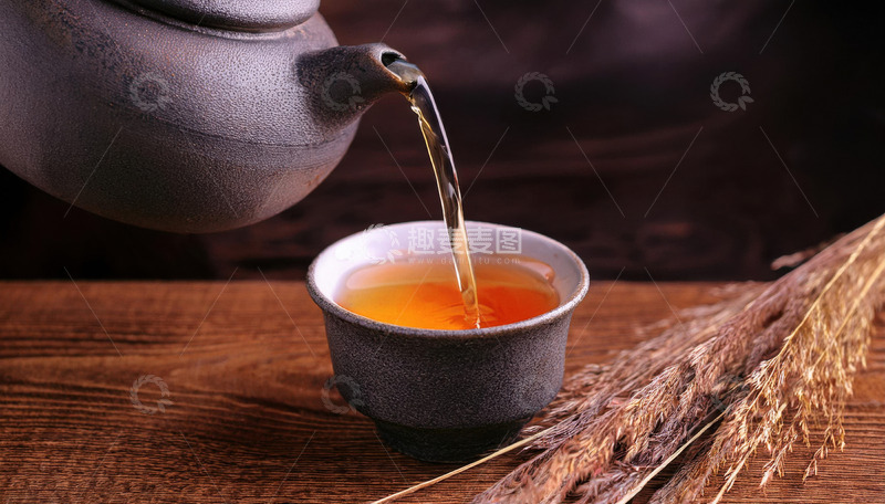 高清大图下载【趣麦麦图】茶壶正往黑色的茶杯中倾倒橙红色的红茶茶汤，背景中有一些干草，营造出一种古朴2
