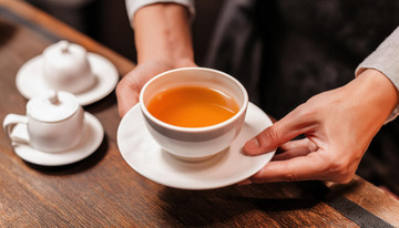 双手端起装有红茶的白色茶杯及茶托的场景1
