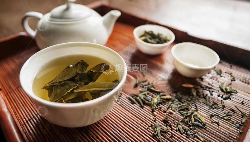 高清大图下载【趣麦麦图】茶杯，杯中盛有泡开的茶叶和茶汤，旁边放着装有干茶叶的小容器，茶具放置在木质茶盘和竹制垫子上，营造出古朴雅致的茶文化氛围