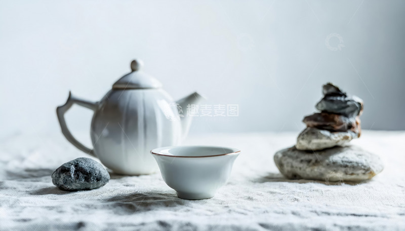 高清大图下载【趣麦麦图】茶杯，旁边摆放着形态各异的石头，有的石头堆叠成造型，背景简洁，营造出一种宁静