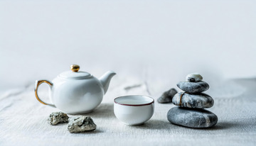 茶杯，旁边摆放着形态各异的石头，有的石头堆叠成造型，背景简洁，营造出一种宁静1
