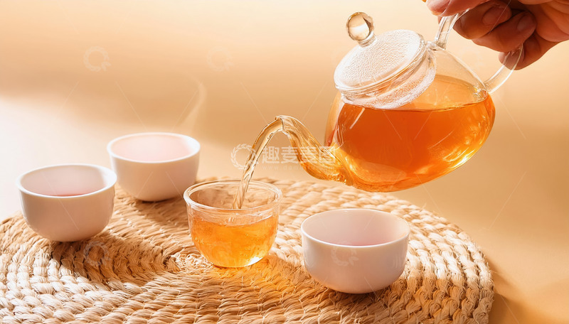 高清大图下载【趣麦麦图】-一只手正拿着透明玻璃茶壶，往白色小茶杯中倒茶，旁边的托盘上还整齐摆放着三只盛有茶汤的白色茶杯，背景简洁，整体呈现出优雅的泡茶1
