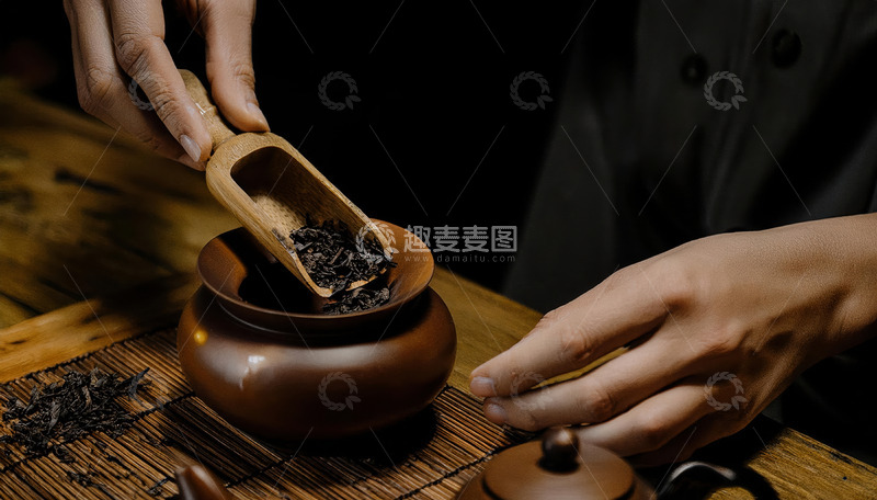 高清大图下载【趣麦麦图】一双手正用木制茶勺将茶叶从容器舀入古朴的陶制茶罐中，背景是木质桌面和竹制茶席1