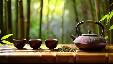 深色茶杯以及一些茶叶放置在竹制台面上，营造出自然