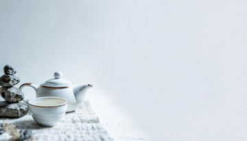 茶杯，旁边摆放着形态各异的石头，有的石头堆叠成造型，背景简洁，营造出一种宁静2