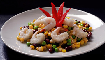 一盘装在白色盘子里的虾仁与玉米青豆等混合搭配顶部有红色装饰的菜肴
