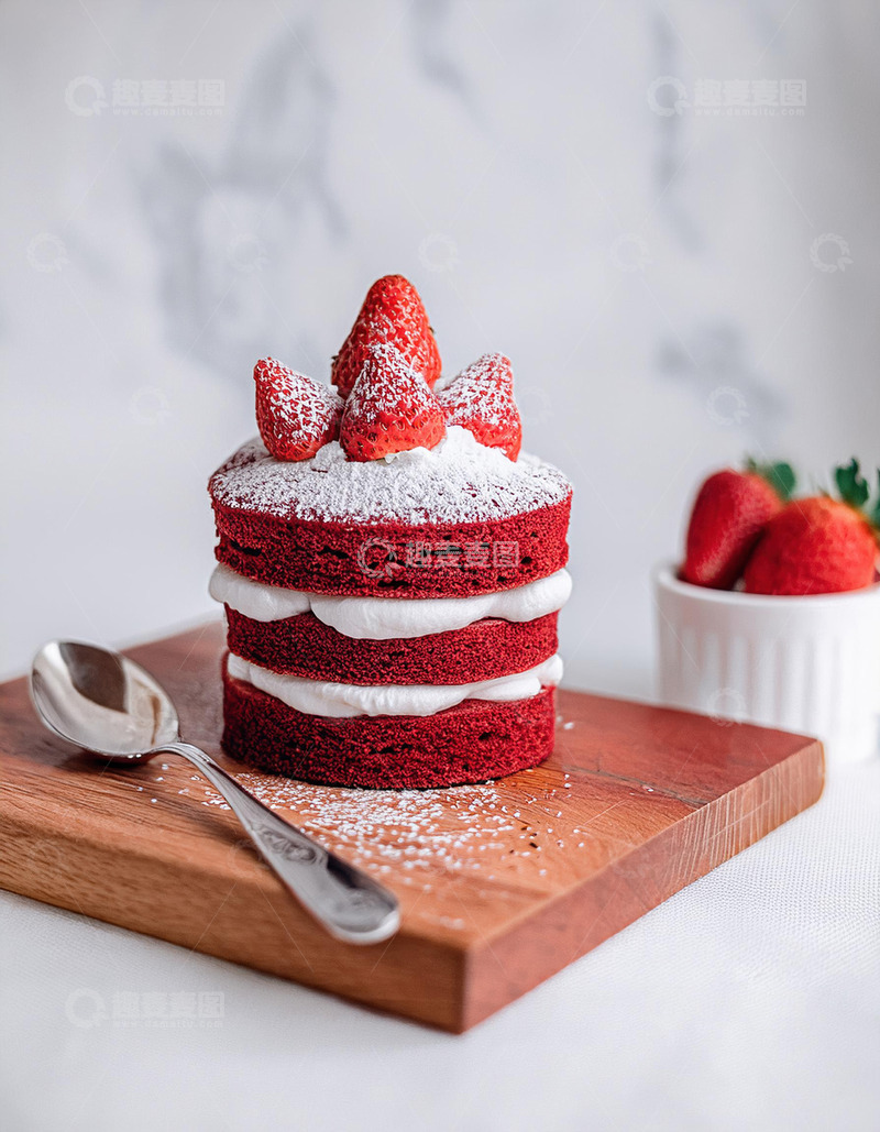高清大图下载【趣麦麦图】-一块放在木制砧板上夹着白色奶油顶部有草莓装饰撒着糖粉的红色蛋糕旁边有银勺2