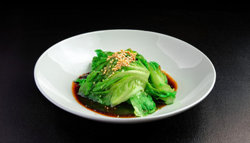 一盘装在白色圆盘中淋有酱汁撒着芝麻的生菜1