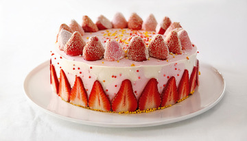 一个放在白色盘子上表面装饰着草莓撒有彩色糖屑侧面有草莓切片的粉色蛋糕1