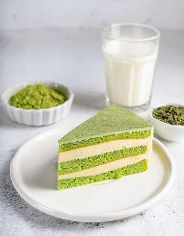 一块放在白色盘子上夹着奶油和豆子的抹茶蛋糕旁边有一杯抹茶饮品1