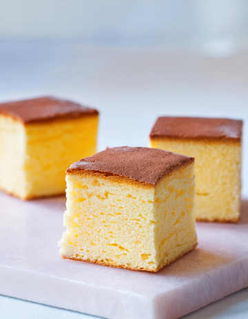 三块整齐摆放在白色盘子上的金黄色方形蛋糕3