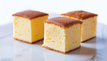 三块整齐摆放在白色盘子上的金黄色方形蛋糕