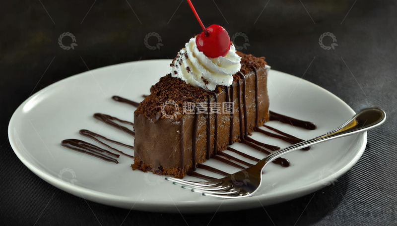 放在白色盘子上淋着巧克力酱顶部有颗樱桃和奶油的巧克力蛋糕1