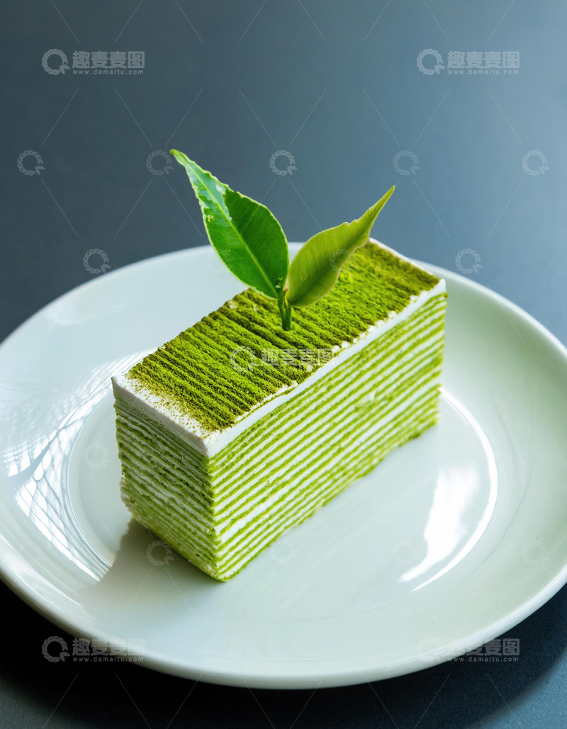 高清大图下载【趣麦麦图】一块放在白色盘子上夹着白色奶油顶部有绿叶装饰的抹茶千层蛋糕2
