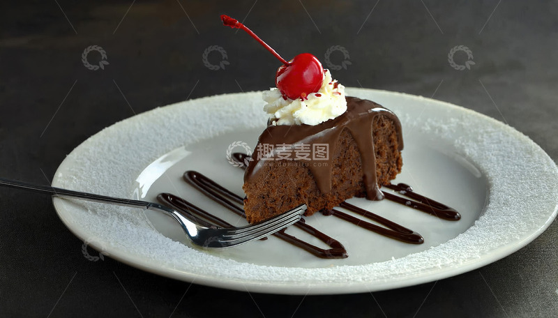 放在白色盘子上淋着巧克力酱顶部有颗樱桃和奶油的巧克力蛋糕3