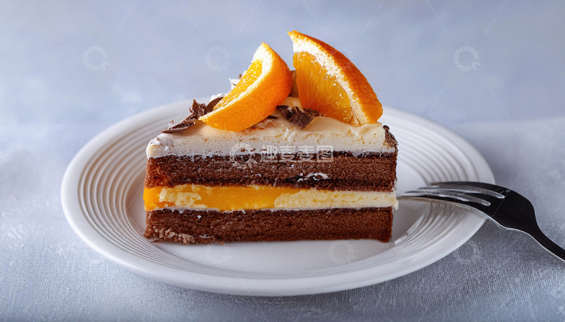 高清大图下载【趣麦麦图】一块放在白色盘子上夹着奶油和橙子片顶部有巧克力片装饰的蛋糕旁边有把叉子3
