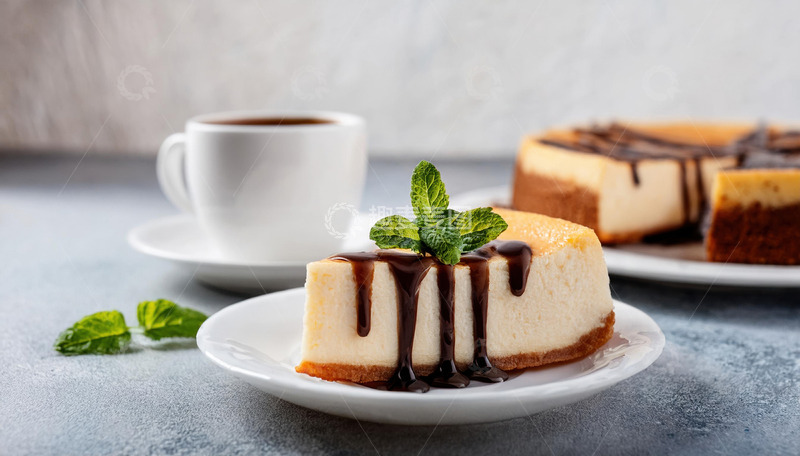 一块放在白色盘子上淋着巧克力酱顶部有薄荷叶装饰的芝士蛋糕旁边有一杯咖啡