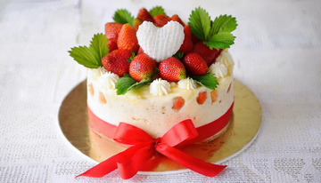 一个放在金色底盘上装饰着草莓绿叶和白色心形物系着红丝带的蛋糕