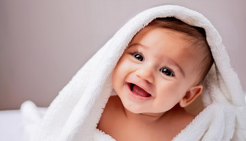 裹着白色毛巾露出开心笑容的婴儿