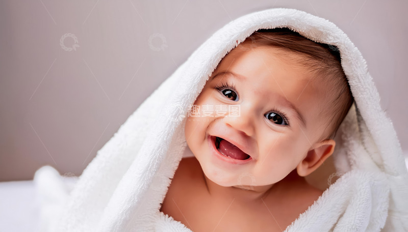 裹着白色毛巾露出开心笑容的婴儿