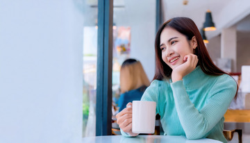 一张女性在室内手持白色杯子面带微笑露出愉悦神情的图片1