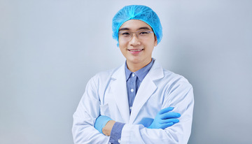 白色医护服头戴蓝色帽子戴着眼镜双臂交叉面带微笑的医生1