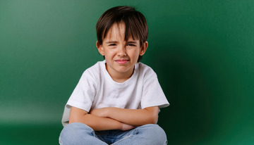 小男孩坐在绿色背景前展现出哀伤神情1
