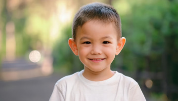 小男孩在户外穿着白色上衣面带微笑