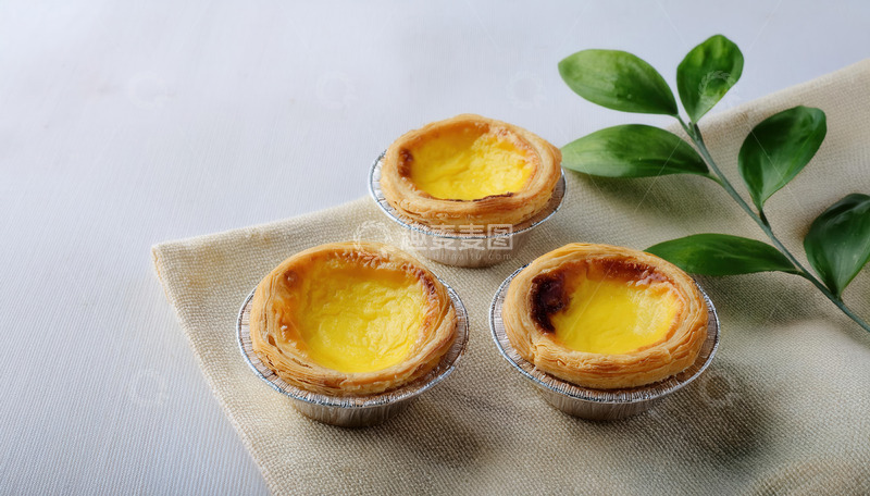 高清大图下载【趣麦麦图】三枚蛋挞配绿叶置于布上