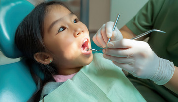 牙医为小女孩仔细检查口腔牙齿