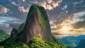 夕阳下植被覆盖的巍峨孤立山峰