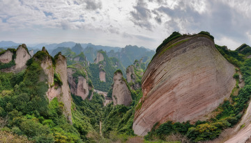 云雾下植被环绕的奇特丹霞山峰