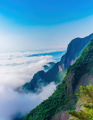 蓝天云海间绿意盎然的陡峭山峦